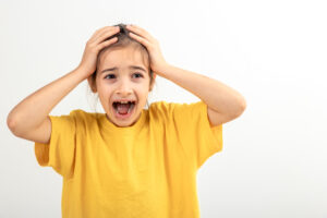 Little desperate girl looking panic, holding her head with both hands.